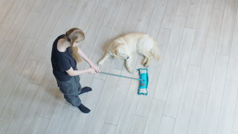 teenage girl cleaning the floor with a mop, golden retriever dog relaxing