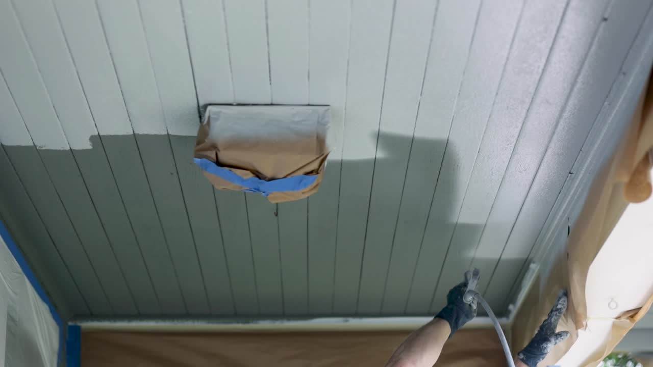 pintar con spray el techo de la casa con pintura blanca, la luz del techo cubierta con papel - plano de ángulo bajo