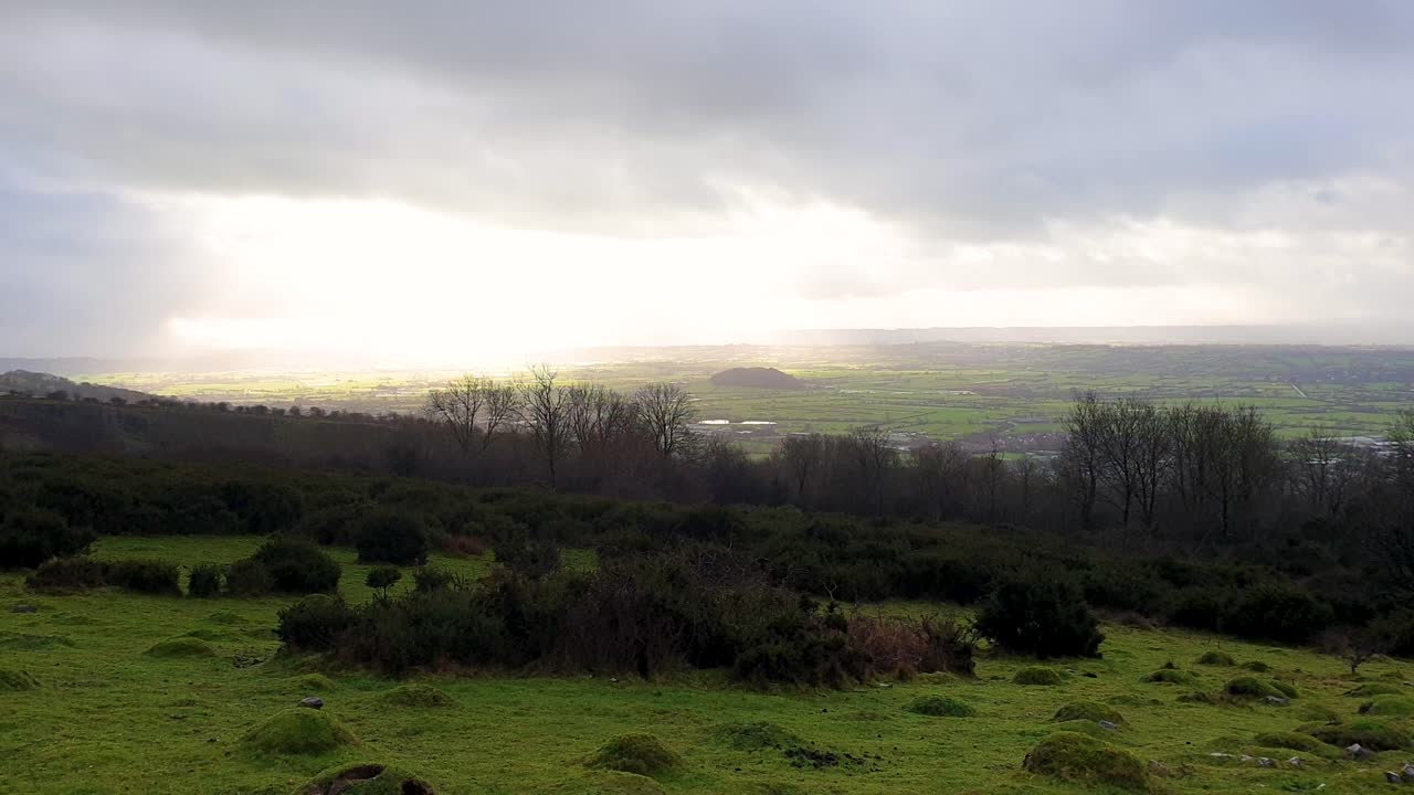 la luz del sol a través de las nubes de lluvia sobre la vista del paisaje de las tierras de cultivo de pastos ingleses desde el desfiladero de cheddar en el distrito de sedgemoor de somerset, al suroeste de inglaterra