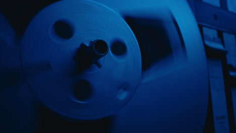 a vintage tape recorder spinning spools in a blue light
