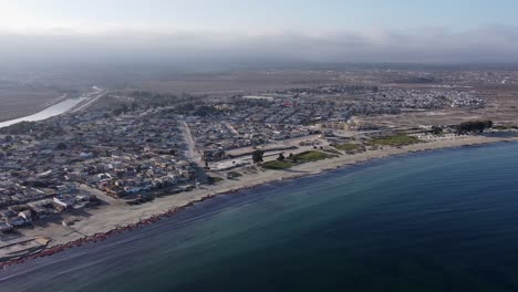 Aerial-descends-to-calm-Pacific-ocean-sand-beach-at-Tongoy,-Chile