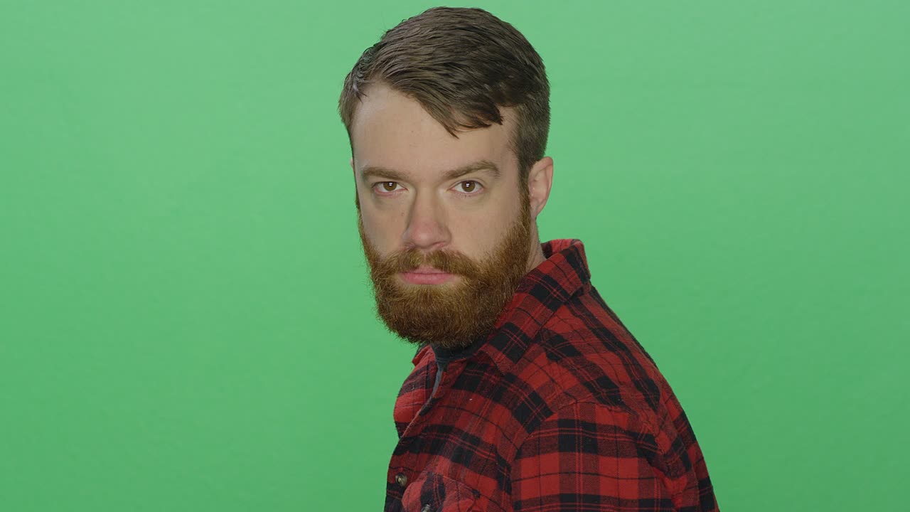 joven barbudo se da la vuelta y mira fijamente, en un fondo de estudio de pantalla verde