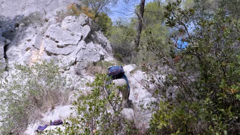 slow motion shot of a man climbing up a steep rocky mountainside following the trail