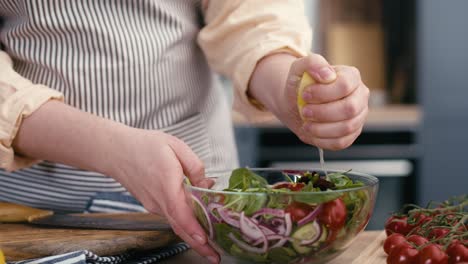 close up of woman squeeze lemon for salad.