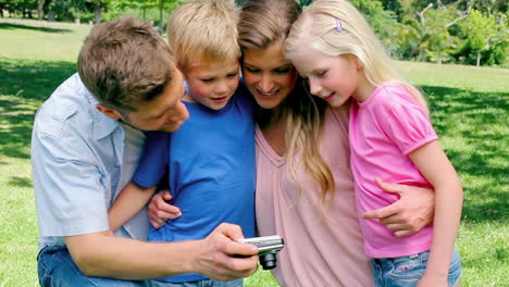 familia sonriendo mientras mira la galería de fotos en su cámara
