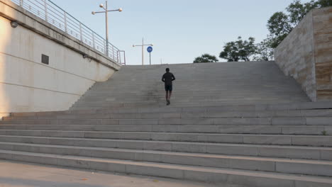 jeune coureur noir qui monte les escaliers et s'entraîne pour le marathon en plein air