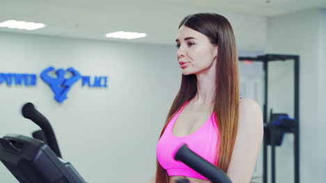 sporty girl training in club. woman smiling while exercise at bike in the gym