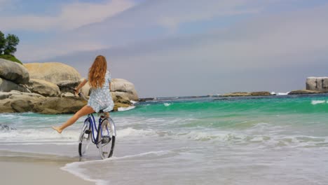 vista trasera de una mujer caucásica montando una bicicleta en la playa 4k