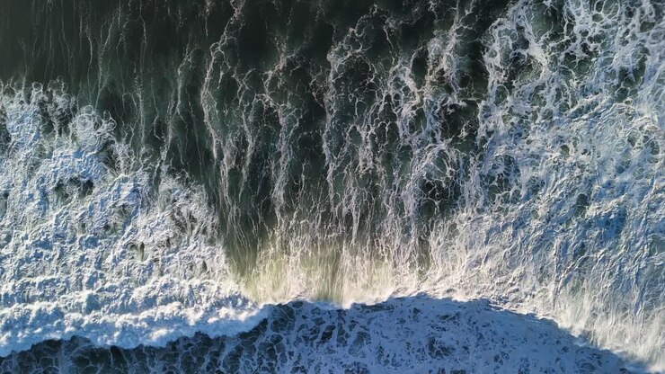 Große Wellen, die im Meer brechen und einzigartige Muster auf der schäumenden Meeresoberfläche erzeugen. Luftaufnahme
