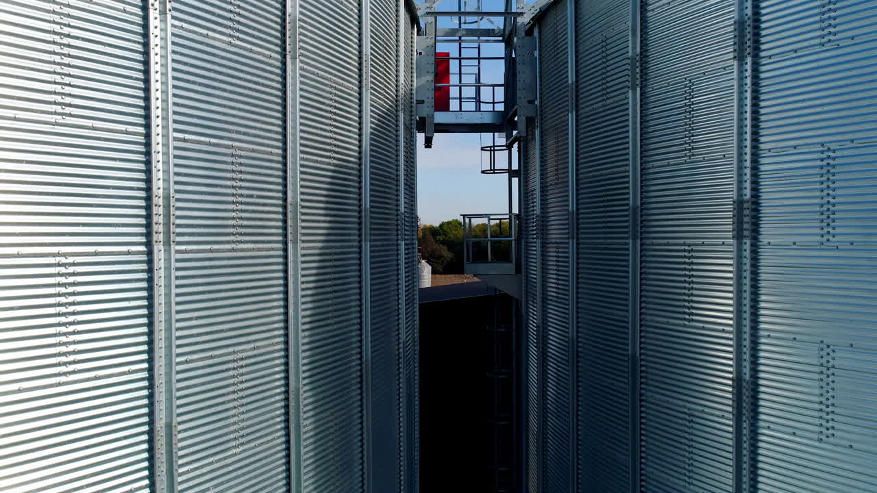 Silver grain elevators outdoors. Exterior of modern aluminum containers for storing harvest. Motion camera top down. Close-up.