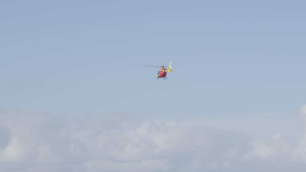 Lifeguard Helicopter flying through cloudy sky.