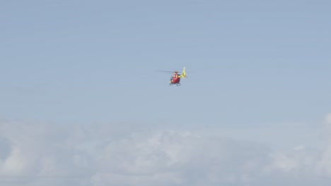 lifeguard helicopter flying through cloudy sky.