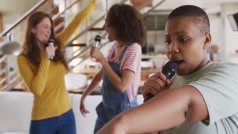 Diverse-group-of-female-friends-having-fun-singing-karaoke-at-home