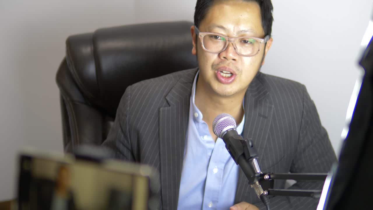 Uomo d'affari asiatico in diretta streaming con smartphone nel suo ufficio a casa