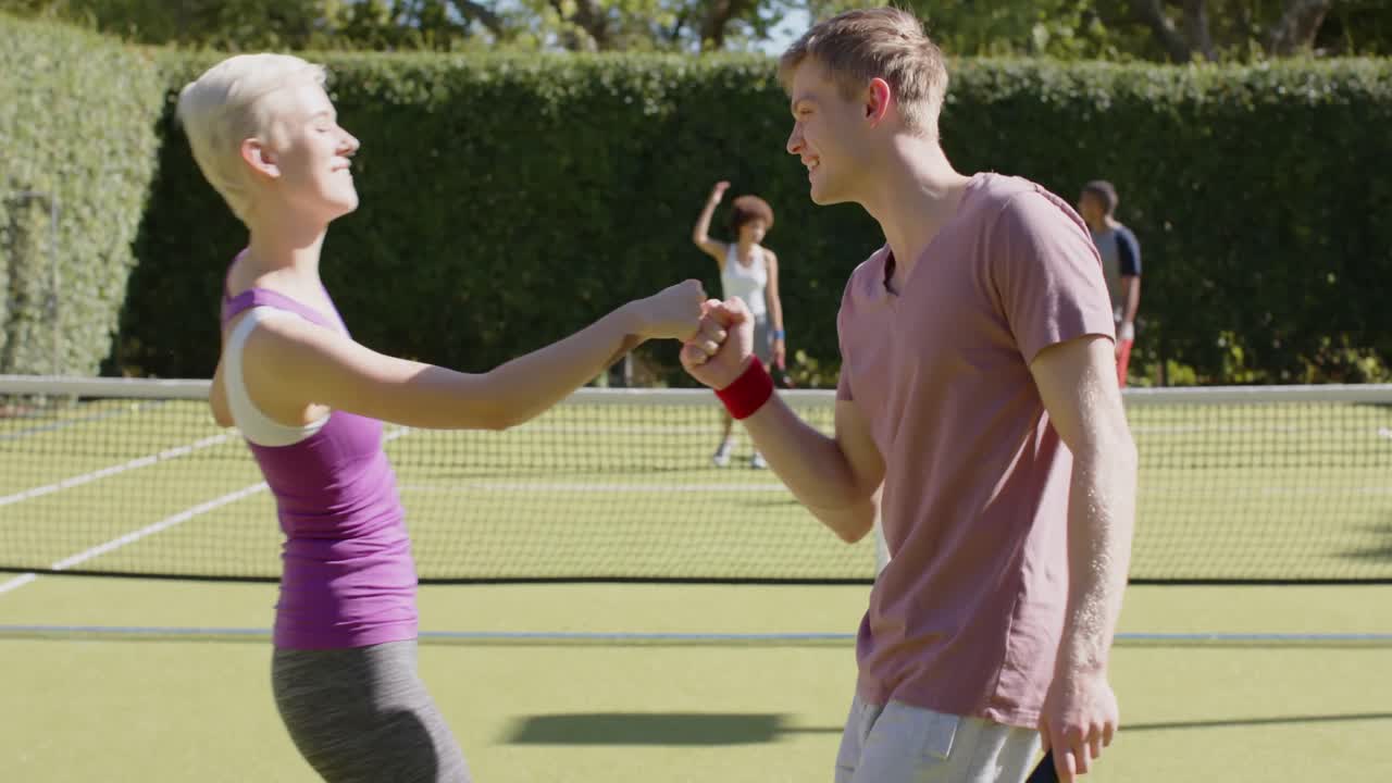 grupo feliz y diverso de amigos jugando al tenis y celebrando en la cancha de tenis