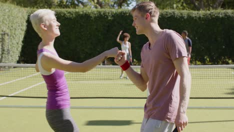 happy diverse group of friends playing tennis and celebrating at tennis court