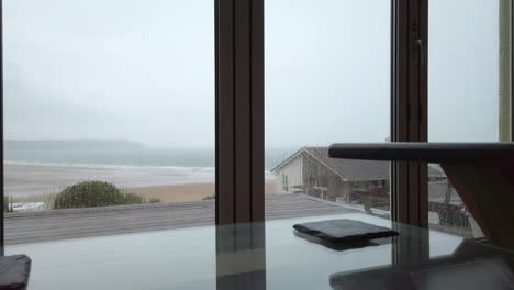 Raindrops-Falling-against-Glass-Doors-in-Slow-Motion-with-a-Coffee-Table-in-Soft-Focus-in-Foreground