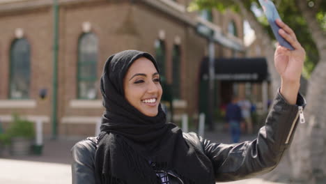 portrait of young middle eastern woman wearing headscarf posing taking selfie photo using smartphone