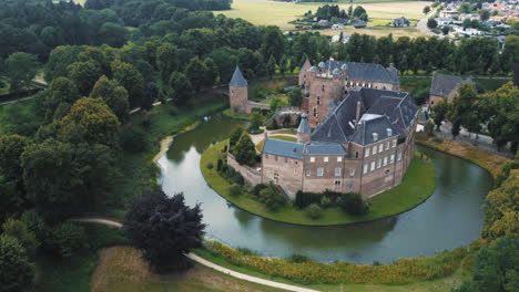 kasteel-huis-bergh,-the-netherlands:-aerial-view-in-orbit-of-the-beautiful-castle-and-appreciating-the-moat,-the-nearby-trees,-the-towers-and-the-nearby-church