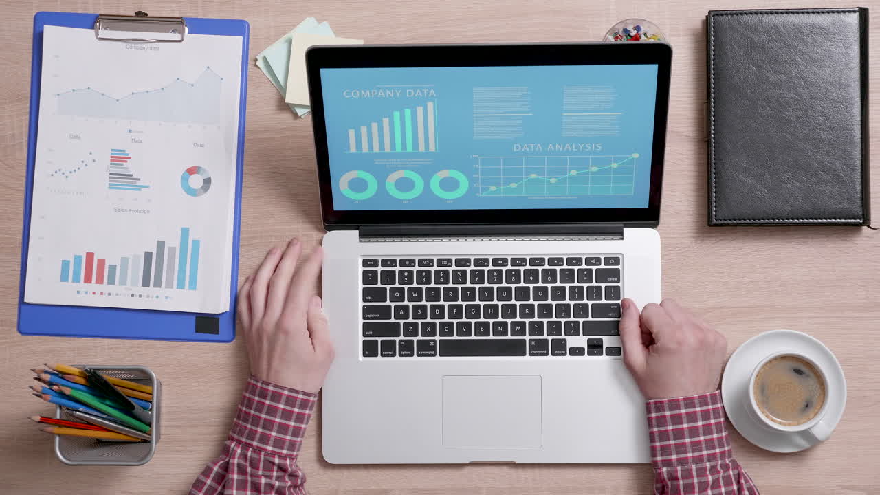 Office workspace with laptop, data charts, and coffee