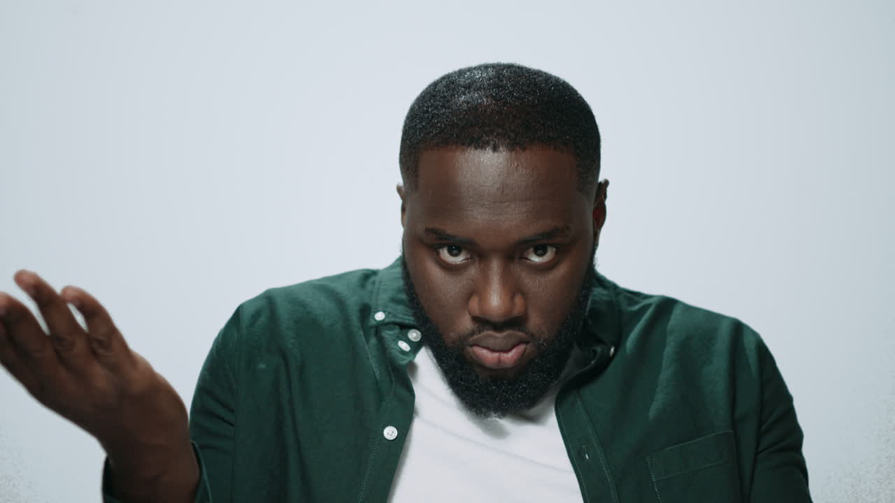 Portrait of displeased african man gesturing with hands at camera in studio.