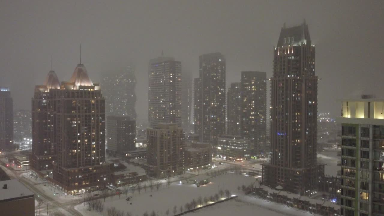 Mississauga, Ontario, Canada, snowstorm, aerial ascend with lights shimmering across buildings