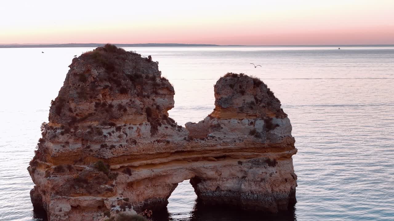 Západ slunce nad mořem z útesů v Portugalsku s loděmi v dálce