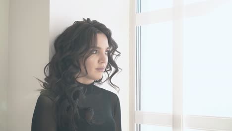 side view unhappy woman with long hair stands near window