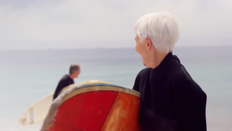 retired couple holding surfboards