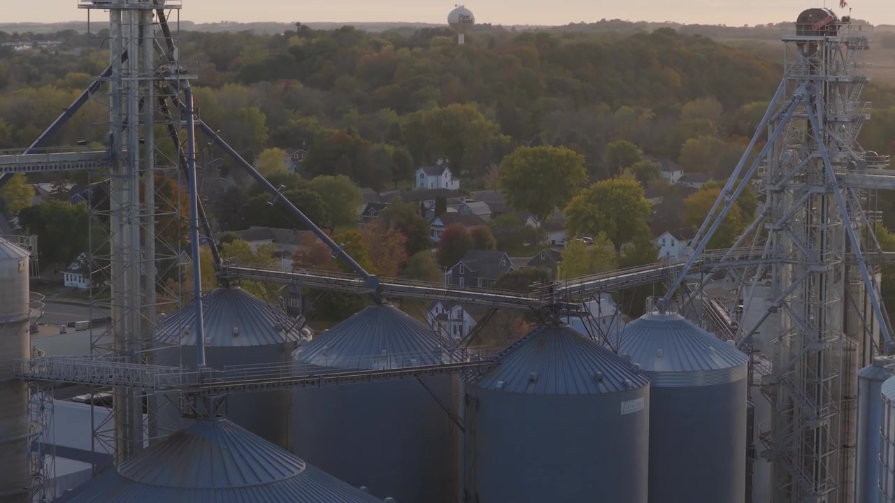 Silos per cereali e strutture di elevazione presso un impianto agricolo a Pine Island, Minnesota, ripresa aerea con movimento dolly del tipico paesaggio del Midwest americano