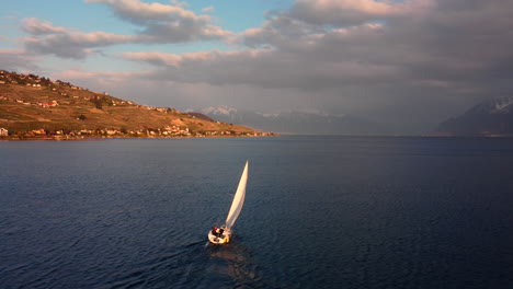 Vuelo-De-Drones-Sobre-El-Lago-Leman-Desde-Vevey,-Con-El-Velero-Yendo-A-La-Frontera-Francesa-Y-Apuntando-A-Las-Montañas