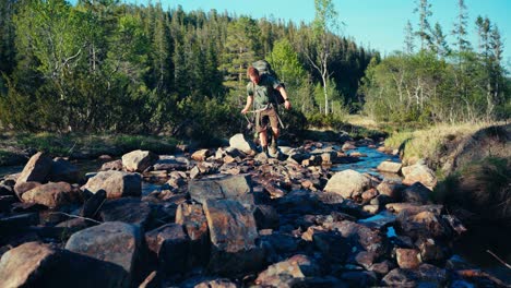 a hiker and his dog trekking through the rocky creek - static shot