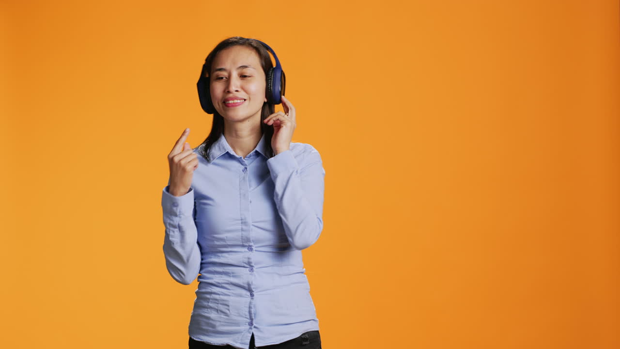 mujer asiática escucha música en auriculares y baila alrededor