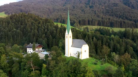 Drone-shot-of-a-small-Church-surrounded-by-a-forest-in-Austria,-Austrian-Alps-from-above,-Europe