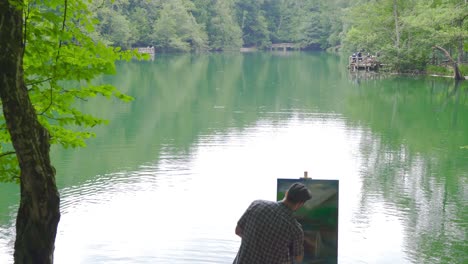 Painter painting against forest and lake.