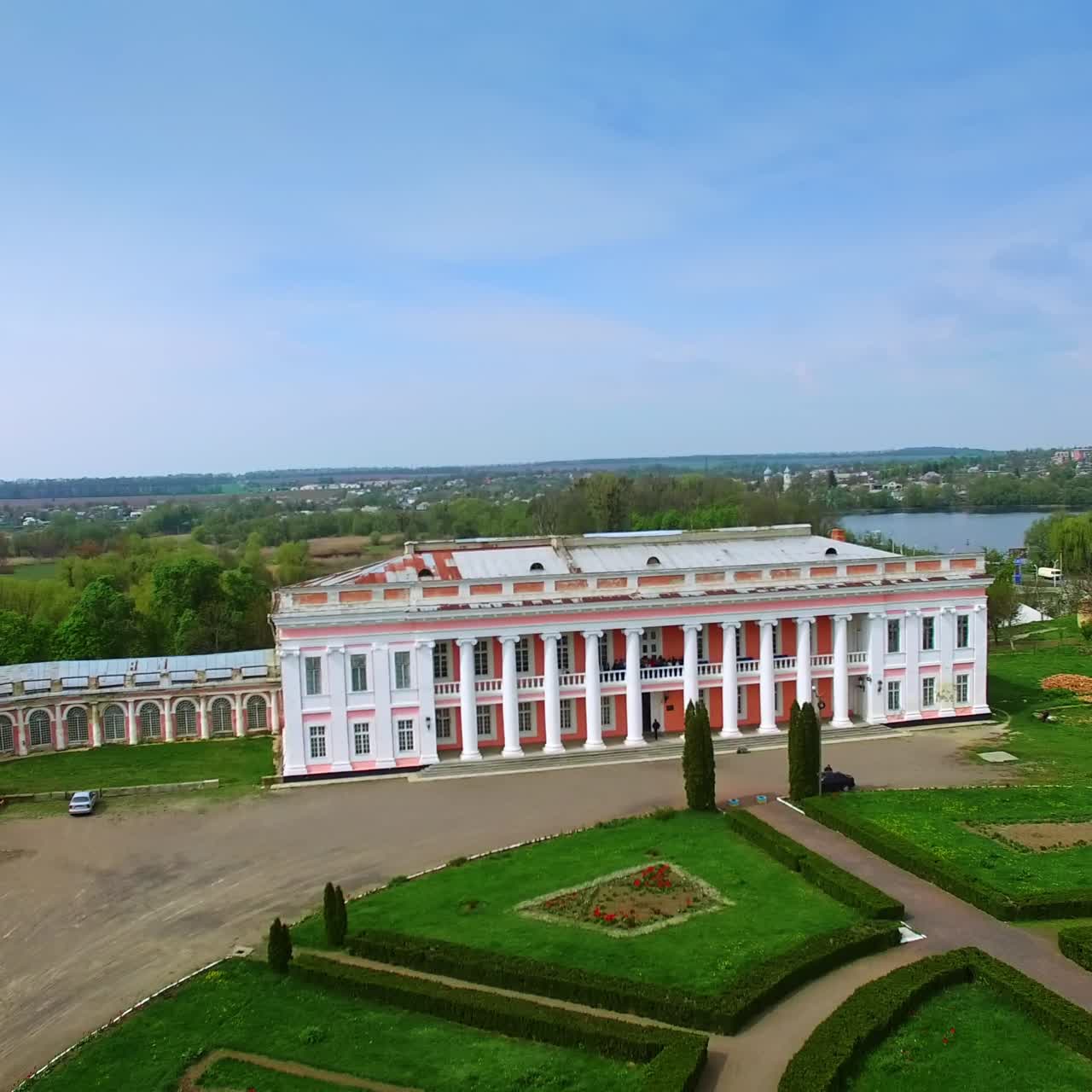 Distancing from a gorgeous two-storied palace with people on balcony. Neat territory in front of the building. Tulchin city, Ukraine
