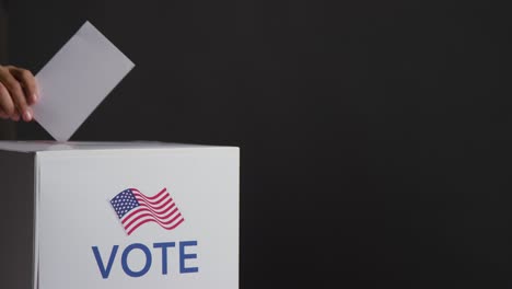 primer plano de los votantes que emiten votos en la urna electoral estadounidense con bandera de los estados unidos contra un fondo negro en cámara lenta