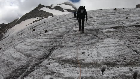 a crystal seeker, alpinist in the swiss alps, hikes a mountain on a glacier with all his equipement, helmet