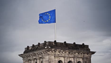 european flag on reichstag building in berlin germany in dramatic mood and cloudy and windy weather