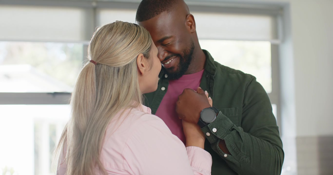 African American couple holding hands at home by window over man's watch, leaning, expressing love