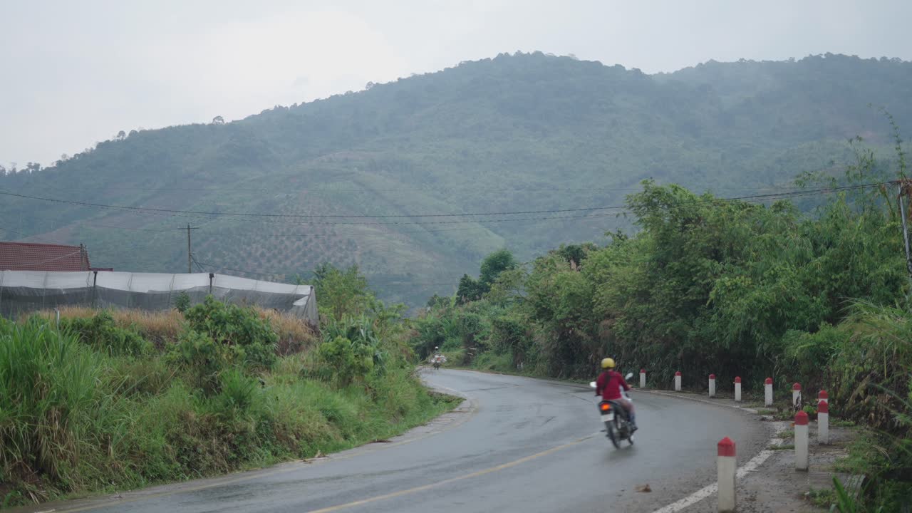 Motorcyclist on a winding mountain road on a rainy day