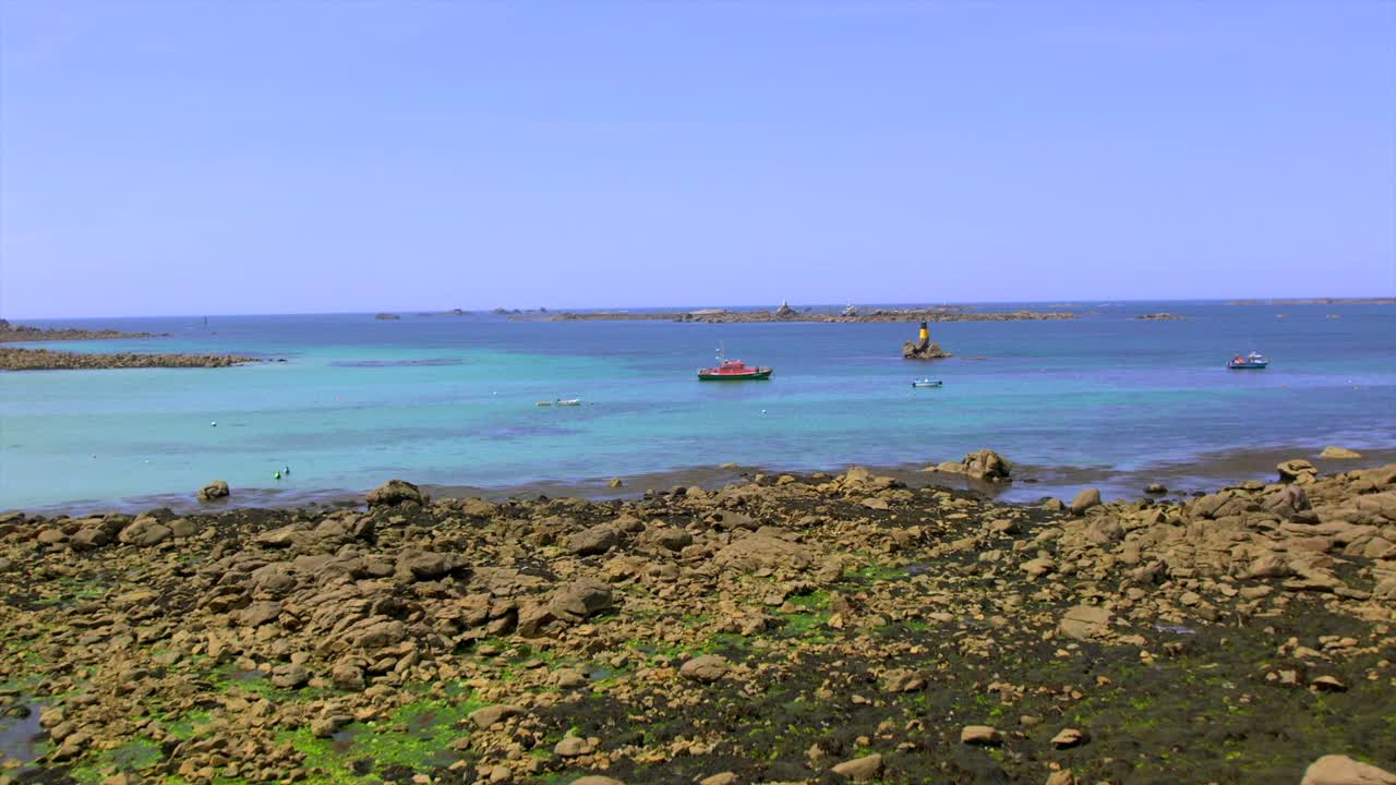 Rocky coastline in Brittany near Brest, France, featuring small boats on clear blue water and rugged rocks along the Atlantic coast. A scenic view of France’s natural coastal landscape.