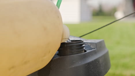 El-Jardinero-Llena-El-Tanque-Del-Cortacésped-Con-Una-Lata-De-Gasolina-Durante-Un-Día-De-Trabajo-Al-Aire-Libre---Primer-Plano,-Tiro-Estático