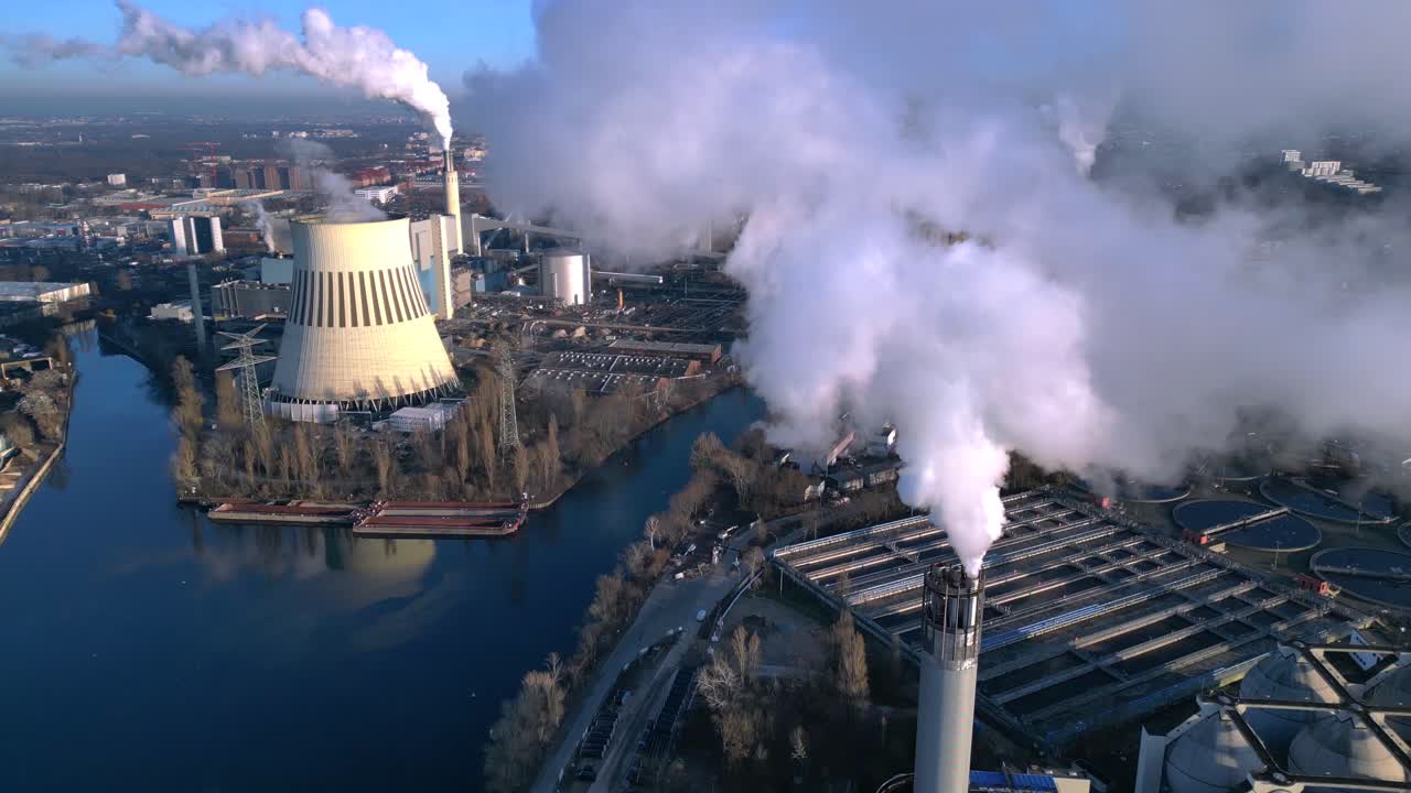 Industrial power Plant chimneys releasing large plumes of smoke pollution into the atmosphere, contributing to environmental damage. Magic aerial view fly through reverse drone