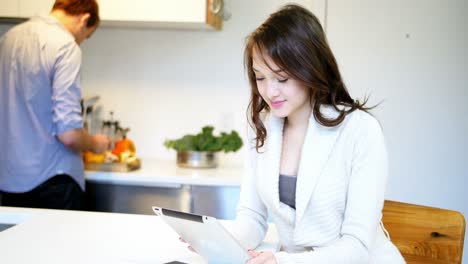 woman using digital tablet while man working in background