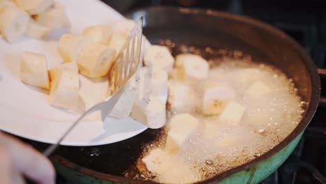 el plátano en rodajas se vierte en una sartén con aceite hirviendo para freír