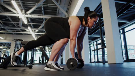 plus-size woman working out with dumbbells in gym