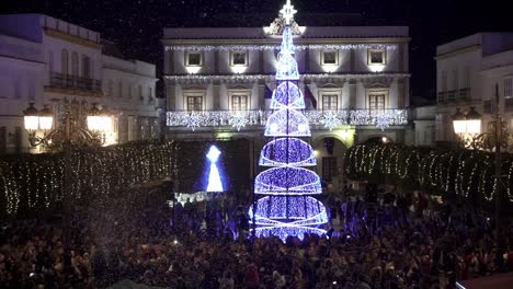 toma manual en cámara lenta de una plaza de la ciudad en medina sidonia en cádiz españa durante un festival de navidad con muchas personas frente a un árbol de navidad azul brillante con una estrella en la parte superior