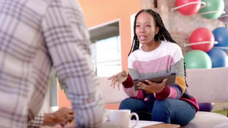 Diverse male and female colleagues in discussion using tablet in casual office meeting, slow motion