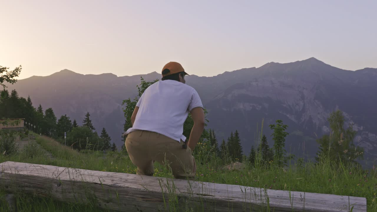 un hombre mirando la vista de la montaña de los alpes desde el borde de la colina, en la parte trasera